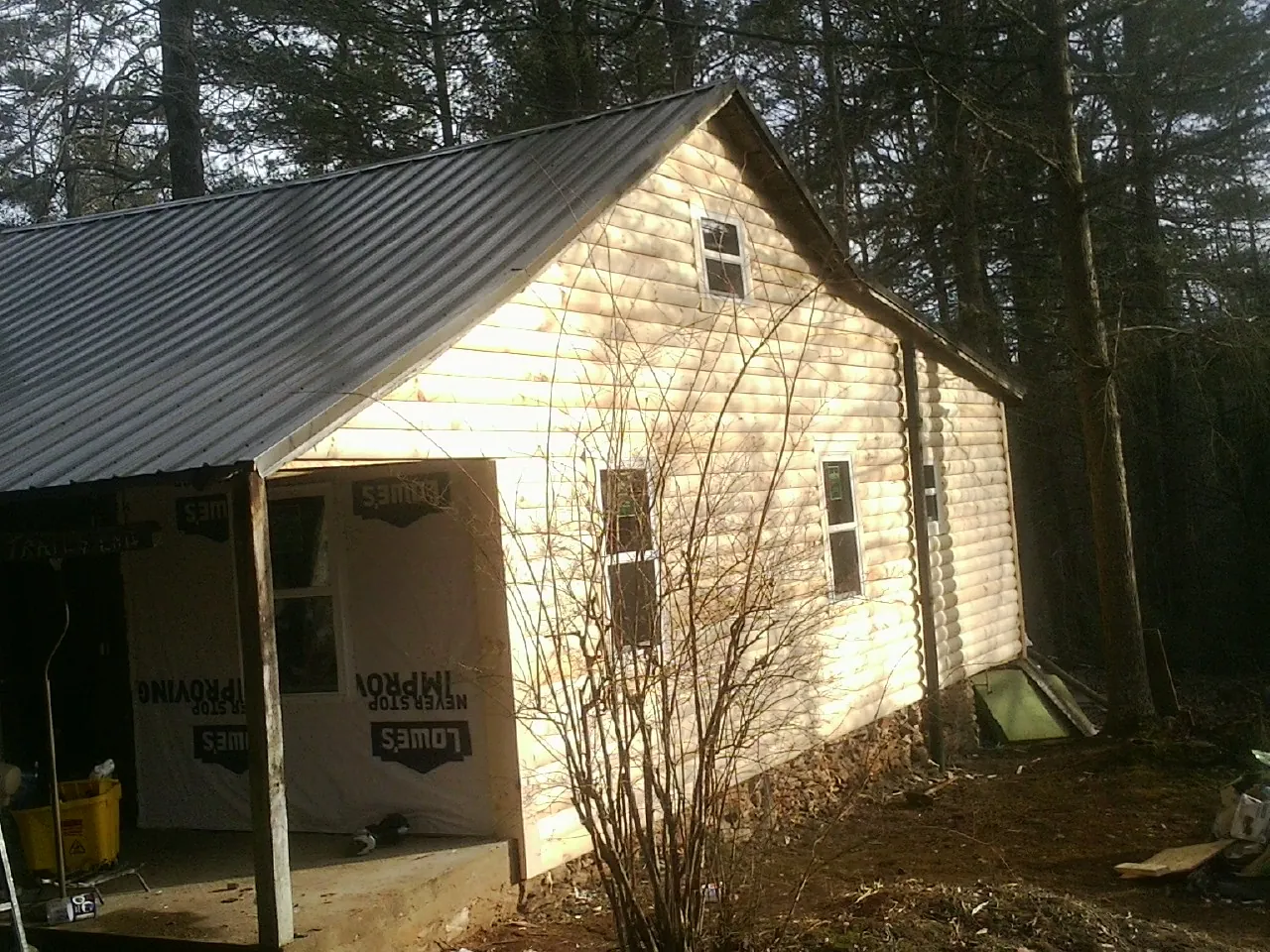 Log siding gable end under a dark metal roof edge in East Earl