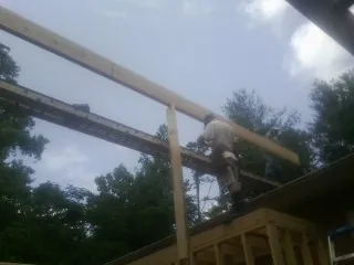 Carpenter setting a ridge beam over a new addition frame — Ice Dam Removal by Roofing Brothers in East Earl