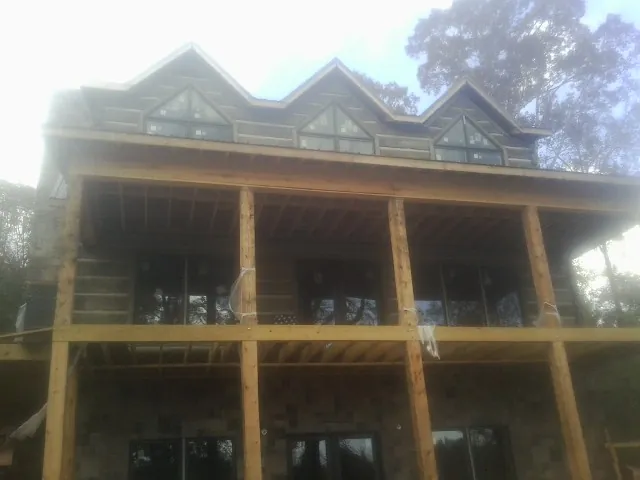 Dormers and porch framing on a large log home under construction — Roof Coating work by our crew in East Earl