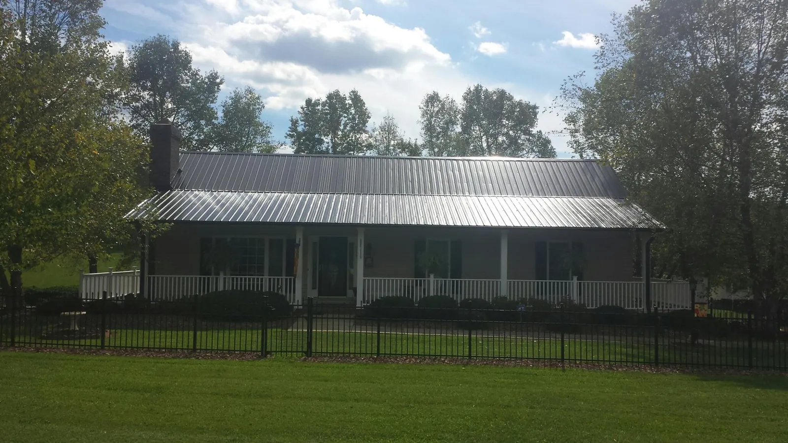Gray metal roof on a brick ranch with a full width front porch — Gutter Guard Installation work by our crew in East Earl