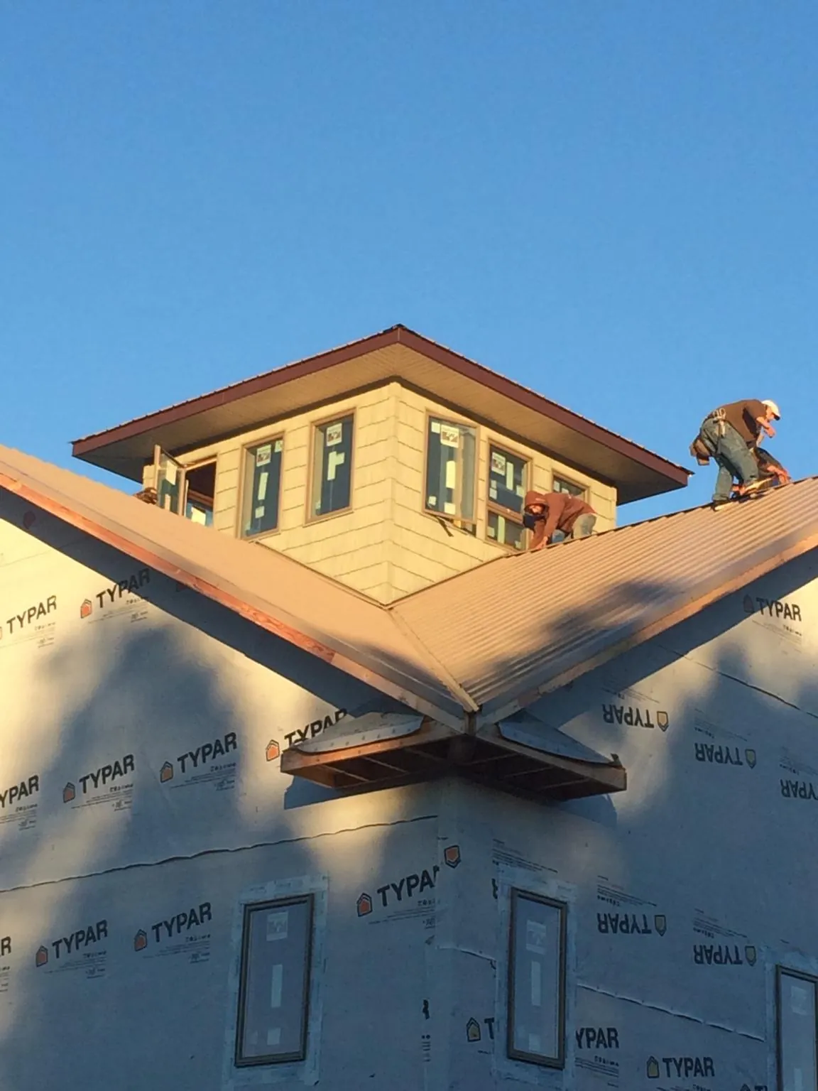 Roofers working around a rooftop cupola on a new metal roof at sunset — Roof Waterproofing in East Earl by Roofing Brothers